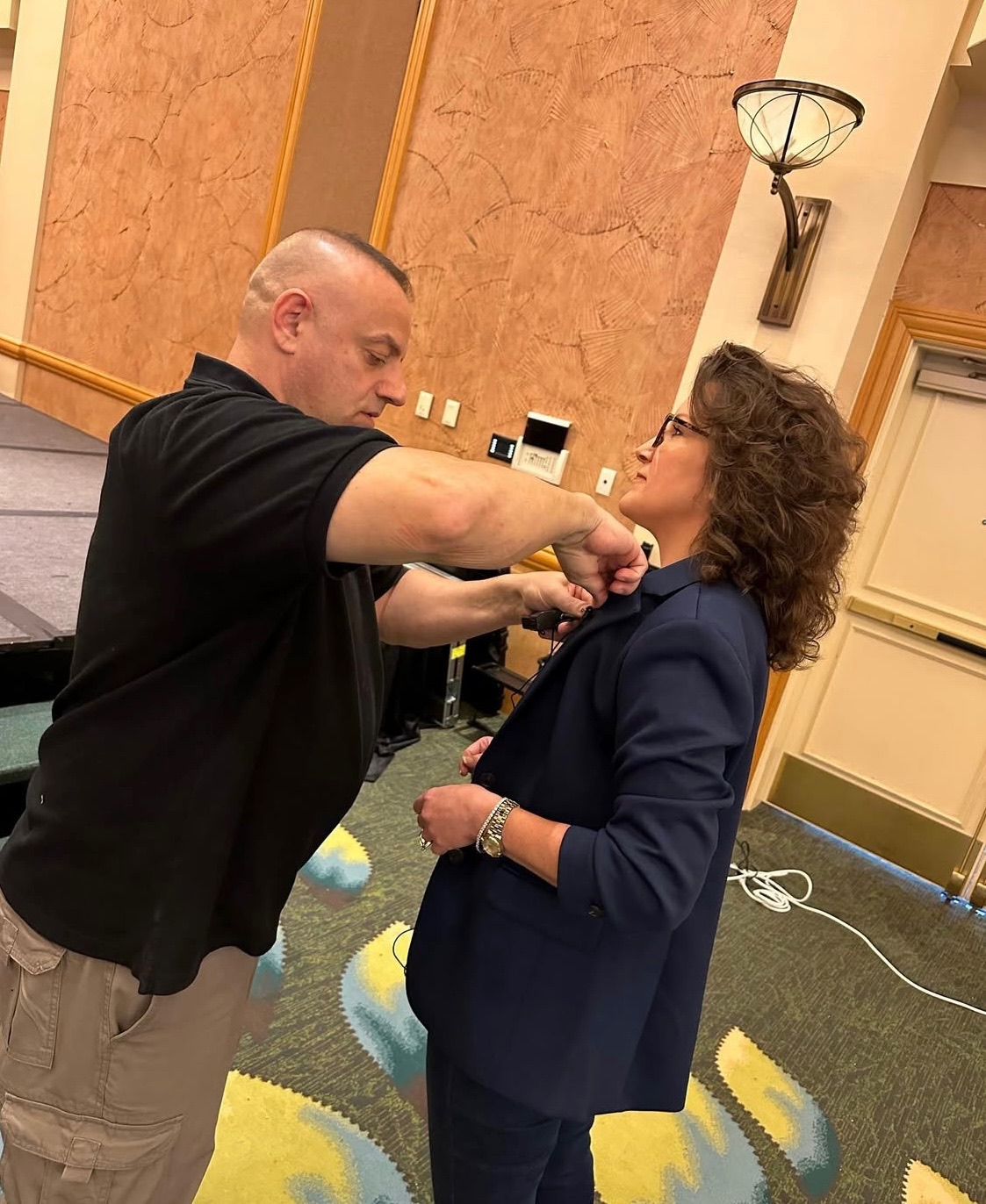 An AV professional clips a lav microphone on Renee Funk before she takes the stage